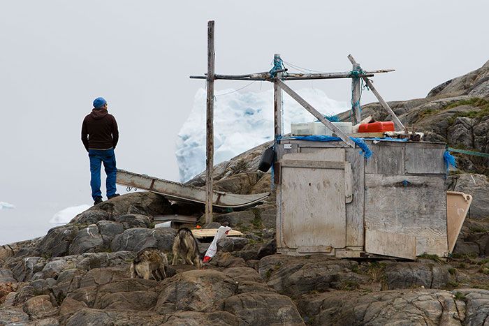 Un pêcheur groenlandais évalue la masse de glace amoncelée devant le rocher sur lequel sont attachés ses chiens.